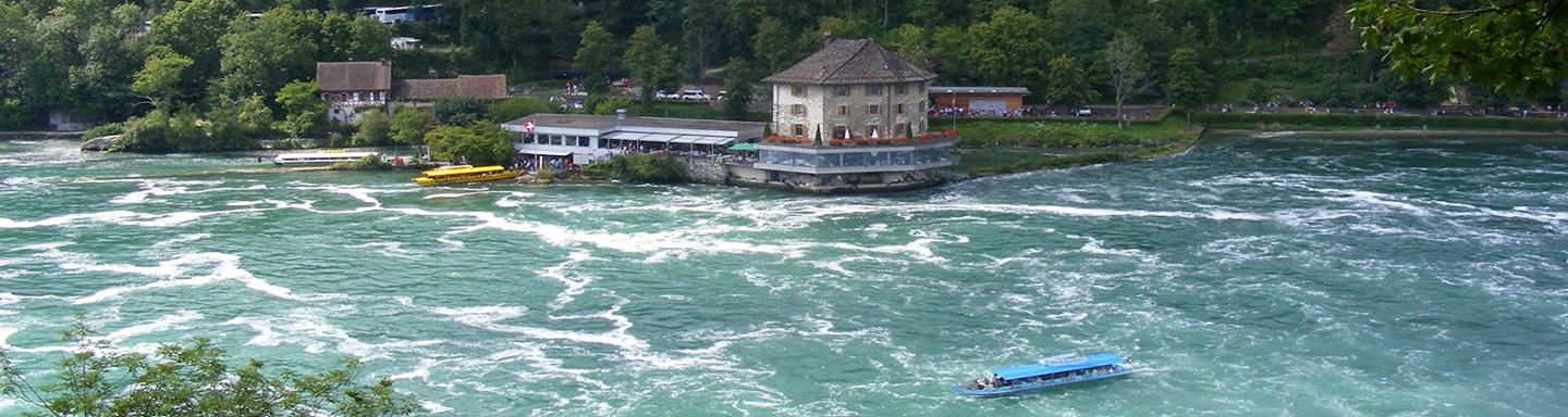 Das etwas unterhalb des Rheinfalls gelegene Schlössli Wörth, am unteren Bildrand ein blaues Rundfahrt-Boot.