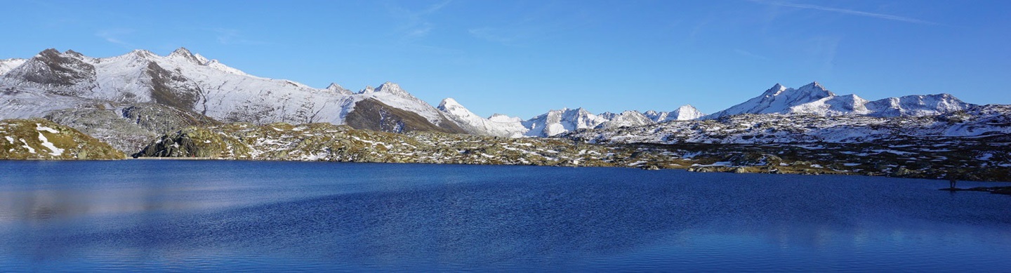 Schroffe, schneebedeckte Berggipfel umrahmen den Toten See auf der Passhöhe des Grimselpasses.