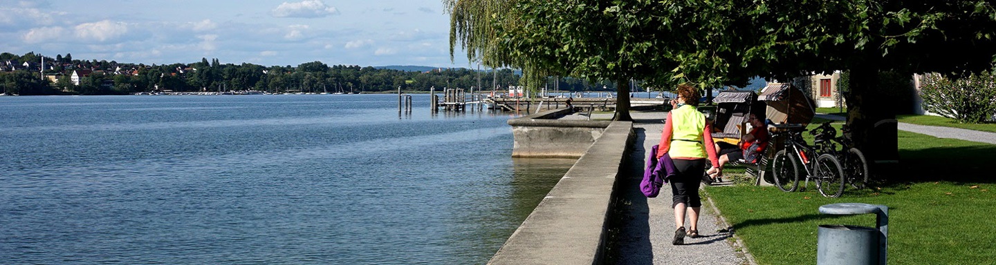 Eine Spaziergängerin auf der Uferpromenade von Steckborn am Bodensee.