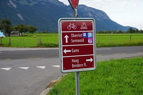 Ein rot-weißes Straßenschild verrät, dass sich im St. Galler Rheintal die Nationalen Schweizer Velorouten Rhein-Route und Seen-Route treffen.