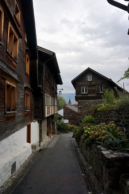 Von Holzhäusern flankierte Gasse in Werdenberg, im Hintergrund die katholische Kirche.