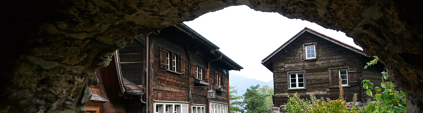 Zwei typische Schweizer Häuser in Werdenberg durch einen Torbogen gesehen.