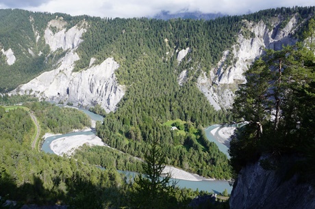 Der türkisblaue Rhein mäandert durch die von Nadelwald und weißen Steilwänden geprägte Rheinschlucht.