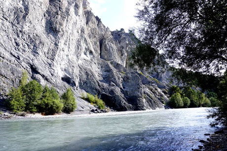 Der zu Füßen einer steilen Felswand vorbeifließende Rhein direkt vom Boden der Schlucht aus gesehen.