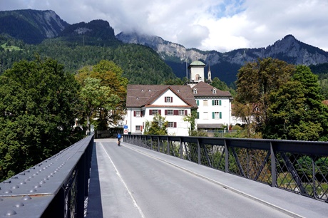 Ein Radler fährt über die Rheinbrücke von Tamins auf Schloss Reichenau zu.