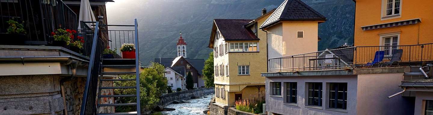 Am Reussufer von Andermatt, im Hintergrund die Kirche St. Peter und Paul.